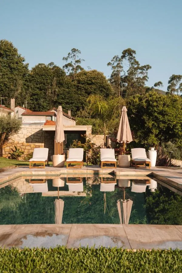 Piscina partilhada ao nascer do sol com casas em pedra ao fundo
